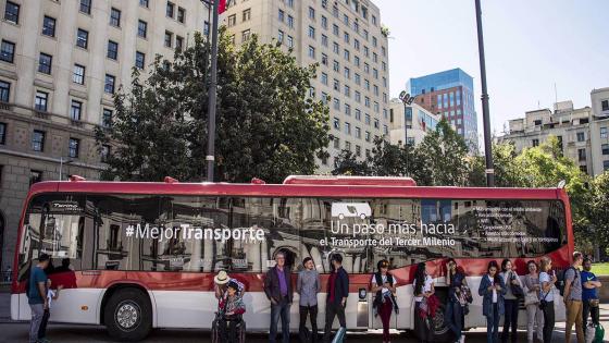 People protect themselves from the sun at the shade of a new ecological Euro 6 model bus, which is displayed in front of "La Moneda" Chilean presidential Palace in Santiago, October 3, 2018. - The Chilean government implemented its new public transport fleet of 200 electric buses and 500 buses Euro 6. (Photo by Martin BERNETTI / AFP) (Photo credit should read MARTIN BERNETTI/AFP via Getty Images)