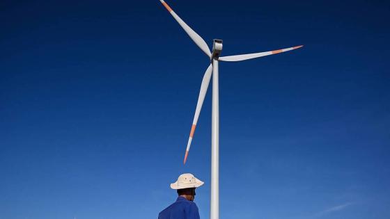 This photograph taken on April 23, 2019 shows a man walking past wind turbines at the Phu Lac wind farm in southern Vietnam's Binh Thuan province. - For power-hungry Vietnam, coal is for now cheaper, more reliable and more familiar than renewables, which currently provide less than one percent of the country's power generation. That number will inch upward to 2.3 percent by next year, according to Vietnam's power plan, with private investment already rushing to fund wind and solar projects. (Photo by Manan VATSYAYANA / AFP) / TO GO WITH Vietnam-climate-energy-coal, FEATURE by Tran Thi Minh Ha with Jenny Vaughan (Photo credit should read MANAN VATSYAYANA/AFP via Getty Images)