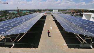 A man walks past solar panels at a solar carport on October 26, 2015 at the Garden City shopping mall in Nairobi. The roof-top solar carport, that was recently launched at the Garden City Mall is Africa's largest solar carport that will cut carbon emissions from power generation through non-renewable energy by 745 tonnes annually, with a total 3300 solar panels used that are capable of generating 1256 MWh annually. AFP PHOTO / SIMON MAINA (Photo by SIMON MAINA / AFP) (Photo credit should read SIMON MAINA/AFP via Getty Images)