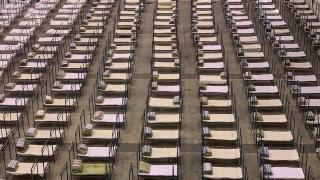 TOPSHOT - Workers set up beds at an exhibition centre that was converted into a hospital in Wuhan in China's central Hubei province on February 4, 2020. - The Wuhan government said it plans to convert three existing venues, including a gymnasium and an exhibition centre, into hospitals to take in patients with mild symptoms of the new coronavirus that has so far claimed more than 400 lives. (Photo by STR / AFP) / China OUT (Photo by STR/AFP via Getty Images)