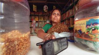 Bangladeshi Anwara Begum sits behind her cellular phone 10 may 2001 in her grocery store in the village of Chaybaria. Anwara Begum is a "phone lady": thanks to a micro-credit from the Grameen Telecom (a member of the Grameen Family of Companies), she could buy a cellular phone that she now rents to other village dwellers. This concept enables Anwara Begum to earm money and gain a social status. More generally, it enables to combat poverty by using technology: as a matter of fact, studies have shown that this concept has positive economic and social impacts on not only the phone owners, but also the communities. (Photo by Jewel SAMAD / AFP) (Photo credit should read JEWEL SAMAD/AFP via Getty Images)