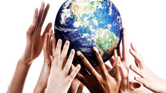 Many mixed hands reaching up to grab a piece of Mother Earth.